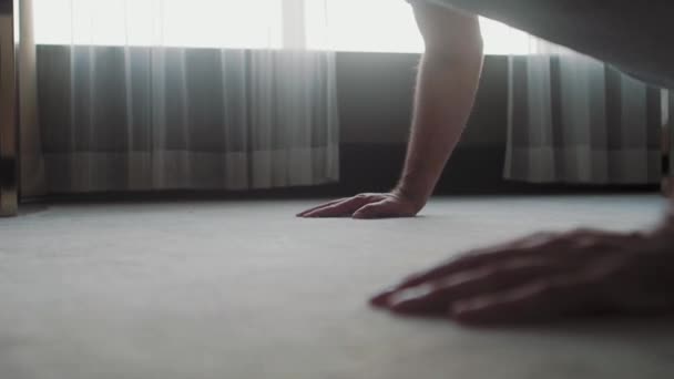 Ένας άντρας με ρούχα σπιτιού πιέζεται από το πάτωμα. Κάνει σπορ στο σπίτι.. — Αρχείο Βίντεο