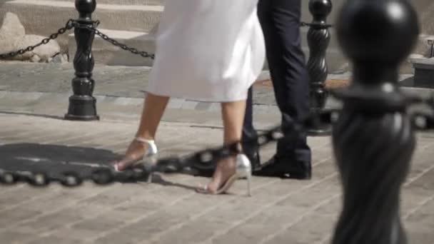 Un hombre y una mujer caminan por un pavimento en una ciudad soleada — Vídeos de Stock