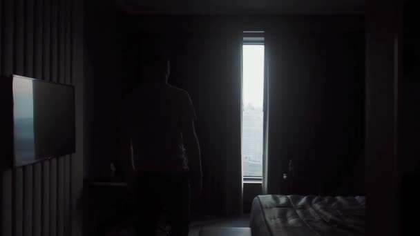 A man in home clothes comes to the window and opens the curtains — ストック動画