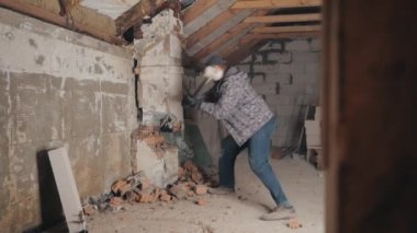 Adam balyozla tuğla duvarı kırıyor.