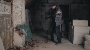 Adam balyozla tuğla duvarı kırıyor.