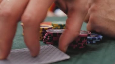 Poker oynayan bir adam kartları kontrol eder.