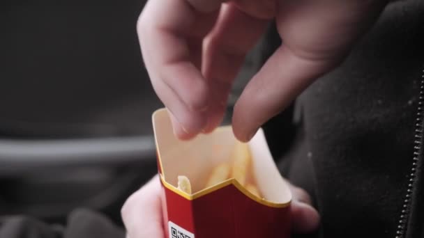 Teenager sits in car and eat French fries — Stock Video