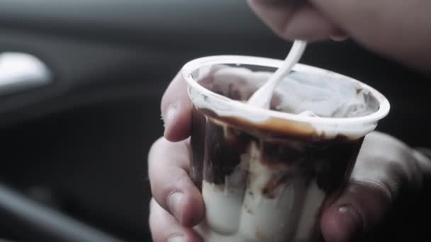 Teen boy sits on front seat of car and eats ice cream — Stock Video