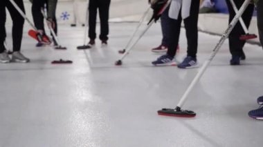 Kadınlar arenada curling oynarlar.