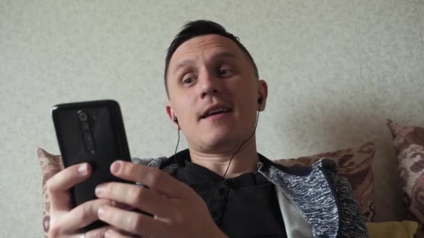 En man hemma chattar på en smartphone — Stockvideo