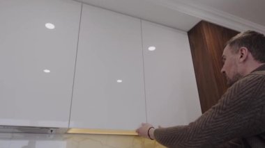 Adam boş mutfak dolabını açıyor.