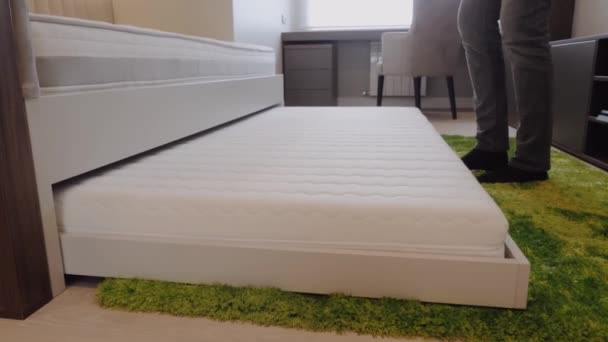 Een man legt een extra bed in een kinderbed. — Stockvideo