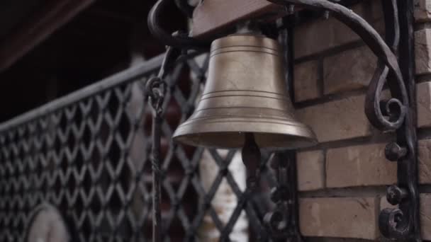 Een bronzen bel hangend aan de muur bij de poort — Stockvideo