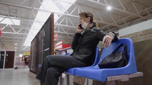 Una donna d'affari in maschera protettiva comunica in un centro commerciale — Video Stock