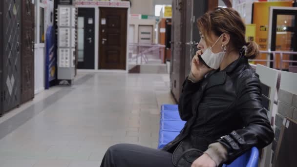 Een zakenvrouw met een beschermend masker communiceert in een winkelcentrum — Stockvideo
