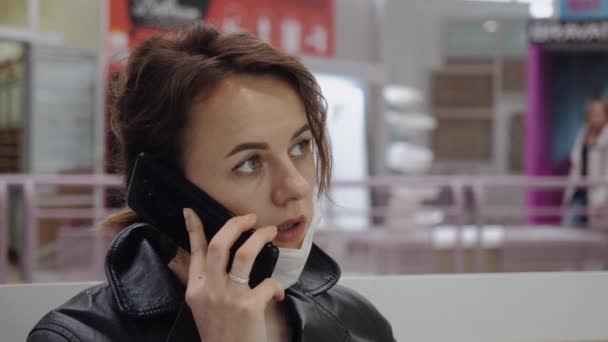 Uma mulher de negócios em uma máscara protetora se comunica em um centro comercial — Vídeo de Stock