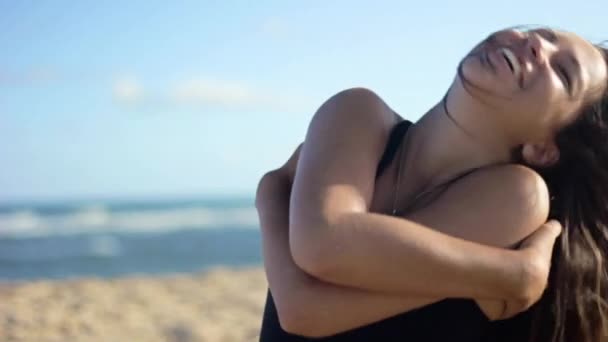 Mujer sentada en la playa riendo — Vídeos de Stock