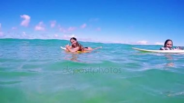 Kızlar sörf sörf tahtaları üzerinde yalan