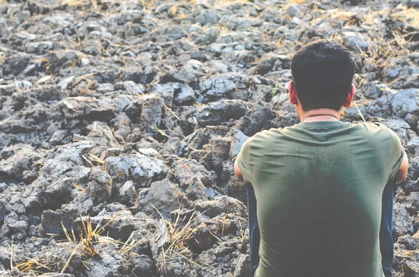 Sad young man sitting on barren ground. Look for a dry rice field.made with vintage filter style — Stock Photo, Image