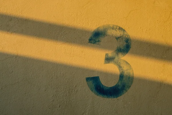 O número 3 na parede sob a sombra das luzes — Fotografia de Stock