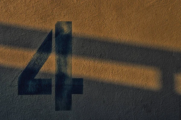 El número 4 en la pared bajo la sombra de las luces — Foto de Stock