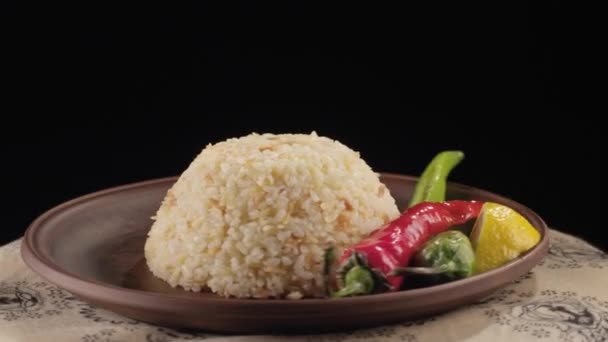 Reis und Pfeffer auf einem Teller auf schwarzem Hintergrund — Stockvideo