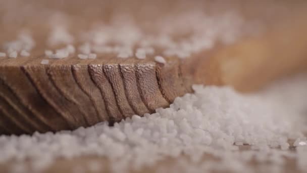Close-up de grãos de sal em uma tábua de corte em uma mesa — Vídeo de Stock
