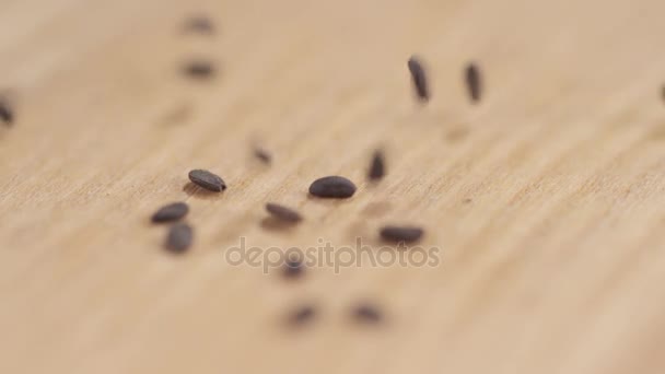 Närbild av korn av svart kummin faller på en tabell — Stockvideo