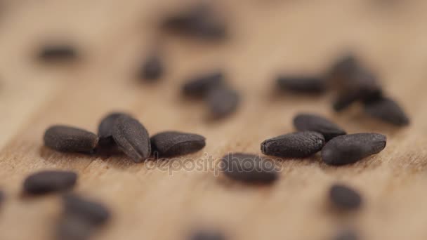 Close-up of of grains of black cumin blown off the table — Stock Video