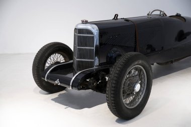 Eski model bir arabanın önünde.