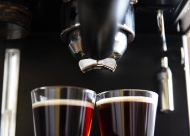 Kahve makinesinin fincanlara kahve doldurduğu yakın plan.