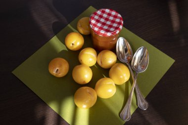 Reçel kavanozunun önünde taze sarı erikler.