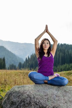 genç kadın bir kayanın üzerinde yoga yaparken