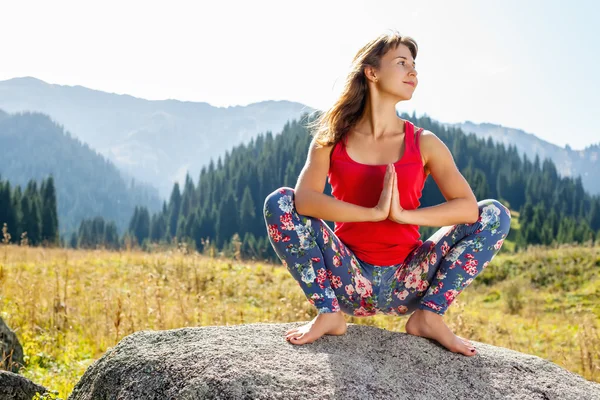 genç kadın bir kayanın üzerinde yoga yaparken