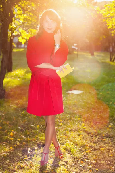 Beautiful woman in red coat posing in autumn Park