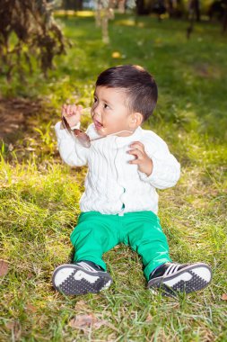 Küçük Asyalı çocuk parkta çimlere oturup çalış