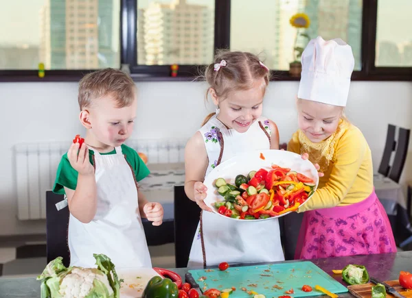 Tres niños lindos están preparando una ensalada en la cocina — Foto de Stock