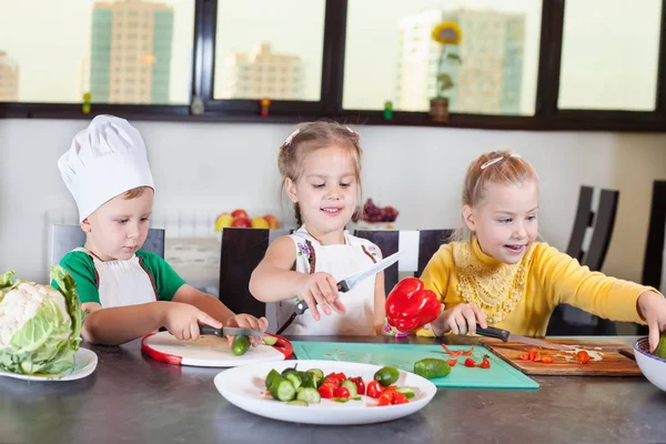 Tres niños lindos están preparando una ensalada en la cocina — Foto de Stock