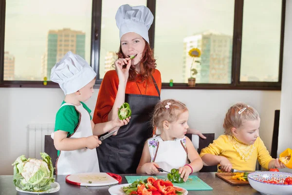 Tres lindos niños con mamá haciendo ensalada de frutas — Foto de Stock