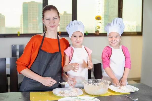 Два прекрасных ребенка вместе с мамой готовят торт — стоковое фото