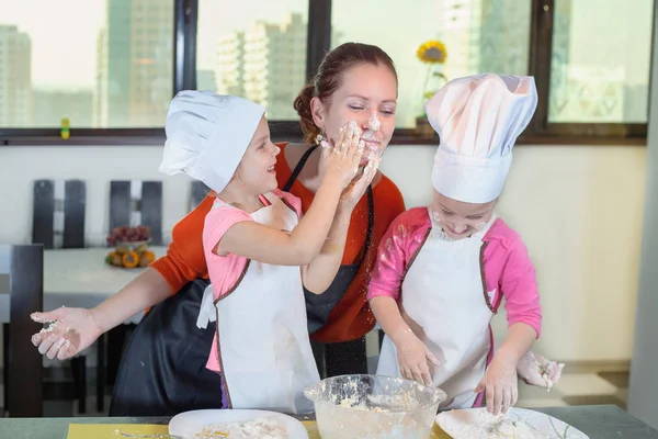 Lovely children together with mother preparing a cake — Stock Photo, Image