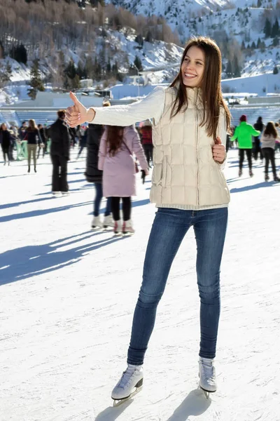 Гарненька жінка катається на ковзанах взимку на відкритому повітрі, посміхаючись обличчям. гори на фоні — стокове фото