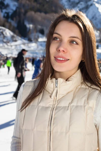 Гарненька жінка катається на ковзанах взимку на відкритому повітрі, посміхаючись обличчям. гори на фоні — стокове фото