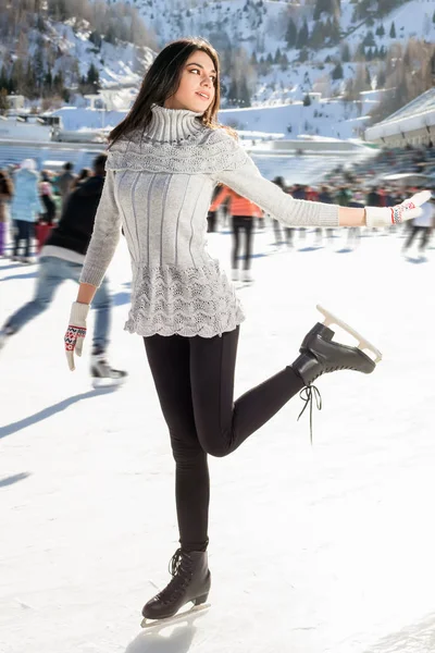 Mujer bonita patinaje sobre hielo invierno al aire libre, sonriente facial. Montañas en el fondo —  Fotos de Stock