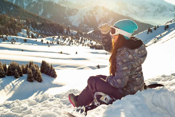 Fille est assise regardant dans le sommet de la montagne de distance au coucher du soleil — Photo