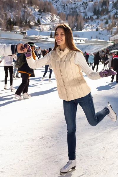 Mujer bonita patinaje sobre hielo invierno al aire libre, sonriente facial. Montañas en el fondo —  Fotos de Stock