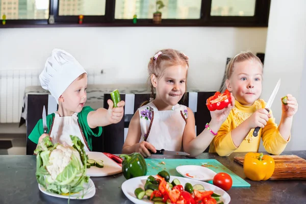 Tres niños lindos están preparando una ensalada en la cocina — Foto de Stock