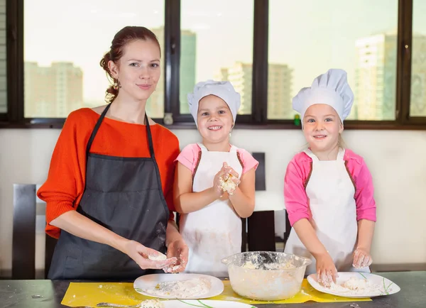 Niños encantadores junto con la madre preparando un pastel — Foto de Stock