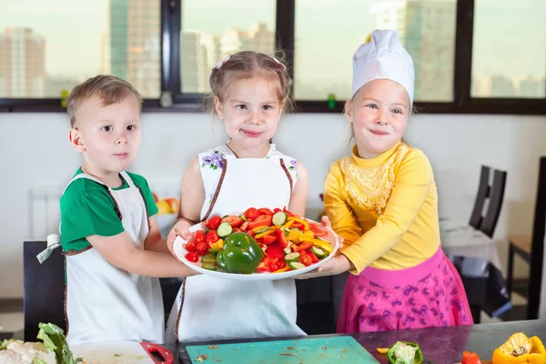 Tres niños lindos están preparando una ensalada en la cocina — Foto de Stock