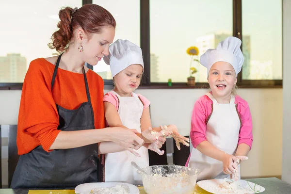 Niños encantadores junto con la madre preparando un pastel — Foto de Stock