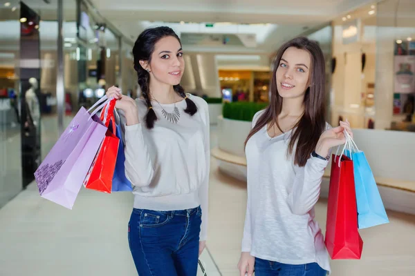 Deux jolies filles marchent dans le centre commercial avec des sacs-cadeaux . — Photo