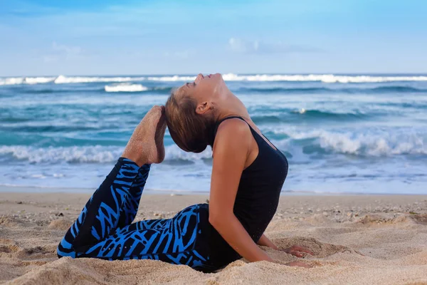 Jeune femme pratiquant le yoga sur la plage au lever du soleil — Photo