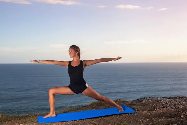 Femme pratique le yoga sur un rocher au-dessus de la mer . — Photo