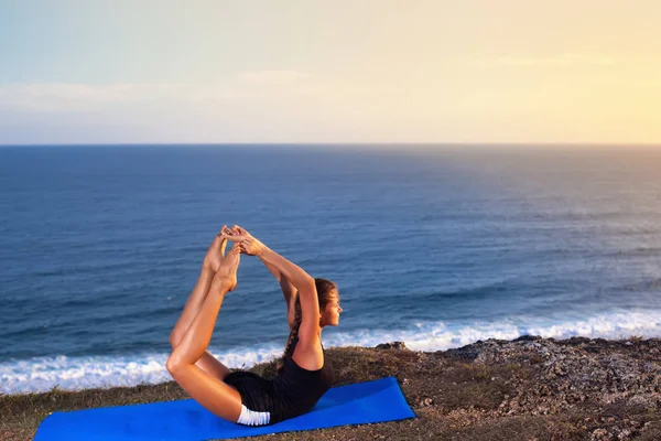Femme pratique le yoga sur un rocher au-dessus de la mer . — Photo